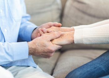 unrecognizable-elderly-couple-holding-hands-at-home